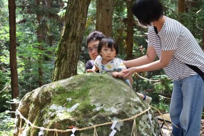 大石にお腹を当てている家族の様子