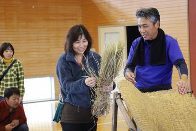 脱穀機で脱穀を体験するオーナーさん
