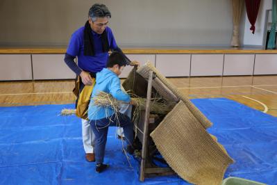 足踏み式の脱穀機を体験する子供
