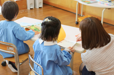 先生とお友だちと一緒に絵本を読む様子